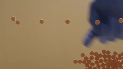 Looking up at a gloved hand sorting pills on a glass table Video stock 127223656