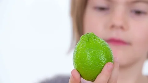 Looking at a green lime in her hand Stock Footage 83725051