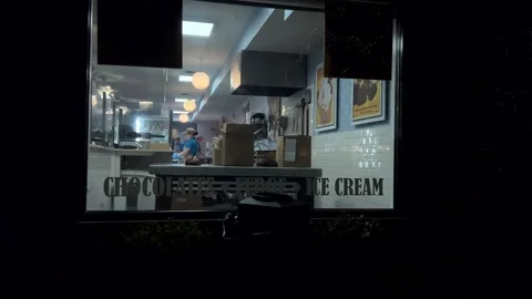 Looking into an ice cream parlor during the evening hours, panning shot Stock Footage 252131072