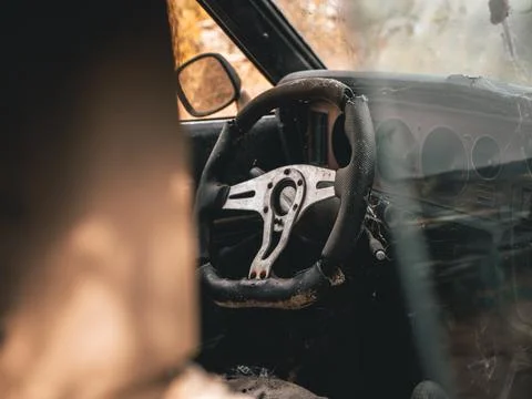 Looking inside interior of junk classic car front seat, dashboard and steering w Stock Photos