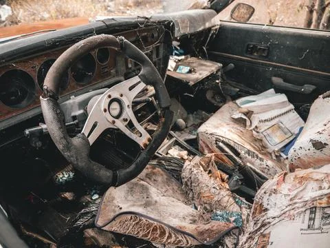 Looking inside interior of junk classic car front seat, dashboard and steering w Stock Photos