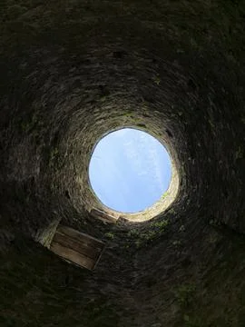 Looking up from inside a rough stone well or shaft, the circular opening fr.. Stock Photos