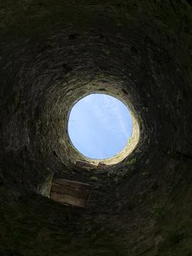 Looking up from inside a rough stone well or shaft, the circular opening fr.. Stock Photos