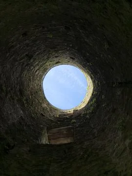 Looking up from inside a rough stone well or shaft, the circular opening fr.. Stock Photos