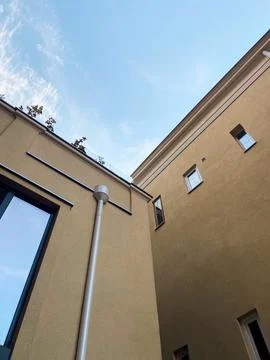 Looking up at the intersection of two modern beige buildings against a bright Stock Photos