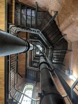 Looking up on the iron staircase inside of a brick building Stock Photos