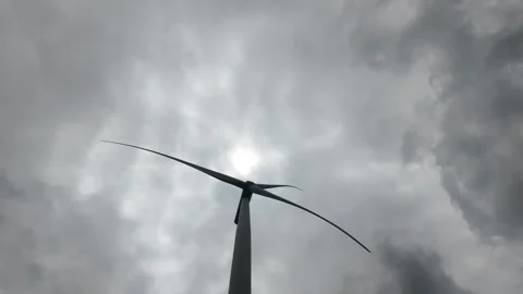Looking up at large wind turbine with rotating blades under cloudy sky Video stock 343197049