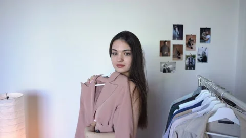 Looking in a mirror at herself Thinking What to Wear Smiling Trying on jacket Stock Footage 148125958