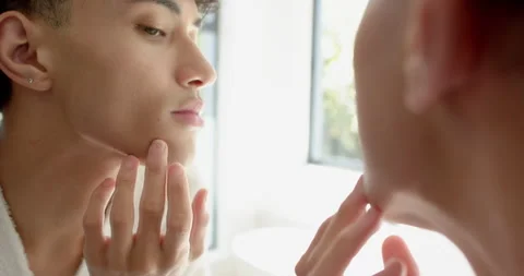 Looking in mirror, person examining face and touching chin at home Video stock 297528342