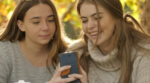 Looking at mobile cell phone technology two teen girls laughing autumn fall Stock Footage 63284854