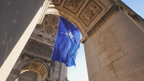 Looking up, the NATO flag is seen hanging from the intricate stonework of an 스톡 동영상 307916918