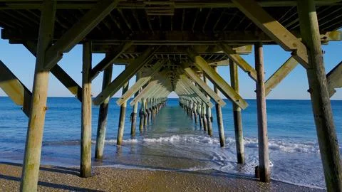 Looking at the ocean from under a pier Stock Photos
