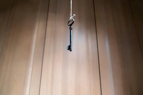 Looking up at old key hanging on string. Vintage wooden background Foto stock