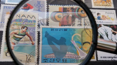 Looking at old postage stamps through a magnifying glass Stock Footage