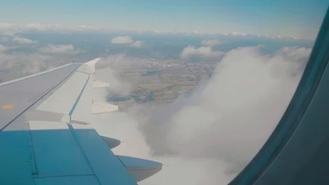 Looking our from an aircraft window at the passing clouds and ground Stock Footage 88765285