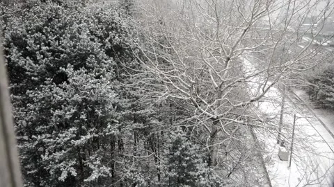 Looking out and down through an open window as snow falls from high floor Stock Footage 328136584