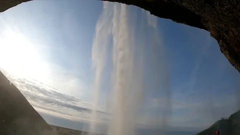 Looking out from behind Seljalandsfoss waterfall at sunset, Iceland Stock Footage 334793535