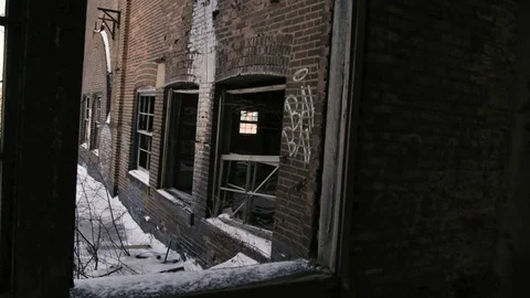 Looking out Broken Windows of Abandoned brick building Handheld pan to left Stock Footage 89944888