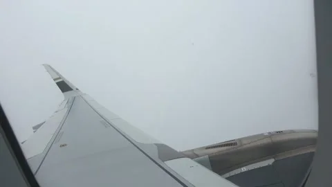 Looking out a cabin window at an engine and wing cutting through clouds. Stock Footage 345352128