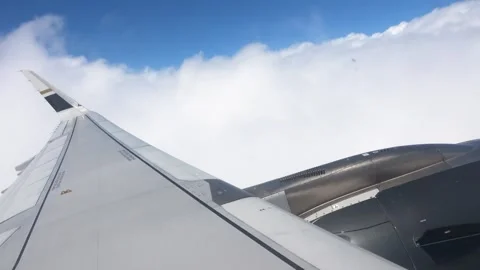 Looking out a cabin window at an engine and wing cutting through clouds. Stock Footage 345352436