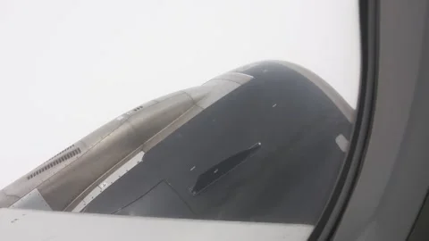 Looking out a cabin window at an engine and wing cutting through clouds. Stock Footage 345352523