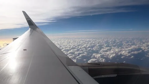 Looking out a cabin window at an engine and wing above the clouds. Stock Footage 345356978