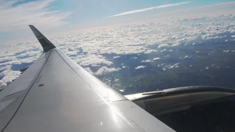 Looking out a cabin window at an engine and wing, banking left above the clouds. Stock Footage 345357684