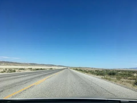 Looking out car windshield at a long road in the Utah desert Stock Photos