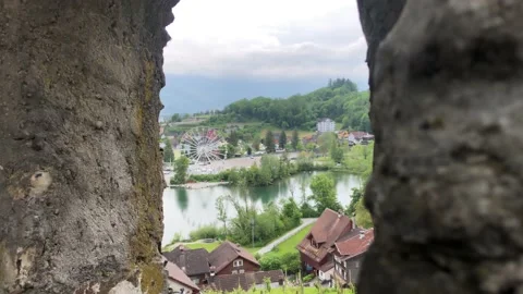 Looking out of the castle of Werdenberg to a small lake and a Ferris wheel Stock Footage 156489991