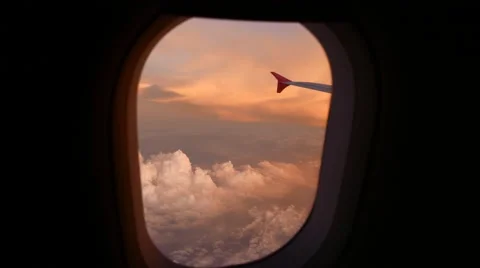 Looking out flying plane window, sunset colours and fluffy clouds Video stock 50541858