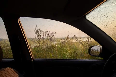 Looking out from inside a car through a window covered in raindrops Stock Photos