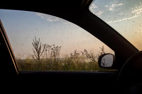 Looking out from inside a car through a window covered in raindrops reveals a Foto stock