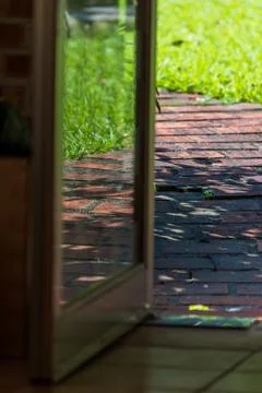 Looking out from inside, one sees the sun-drenched red brick walkway and lu.. Stockfoto's