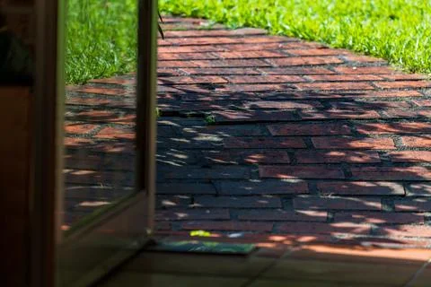 Looking out from inside, one sees the sun-drenched red brick walkway and lu.. Fotos Stock