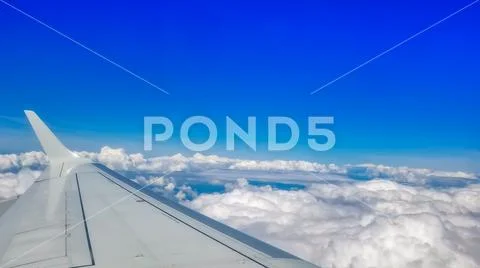 Looking out through an airplanes porthole window during a flight. Stock Photos