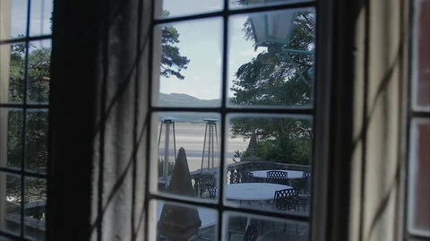 Looking out a window onto patio and beach at an Italian Style Village. Stock-Footage 128502742