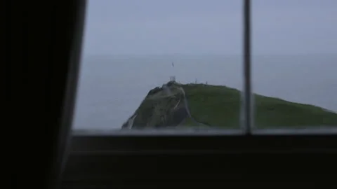 Looking out window on stormy day at sea and flag on hill in Devon Stock Footage 136893566