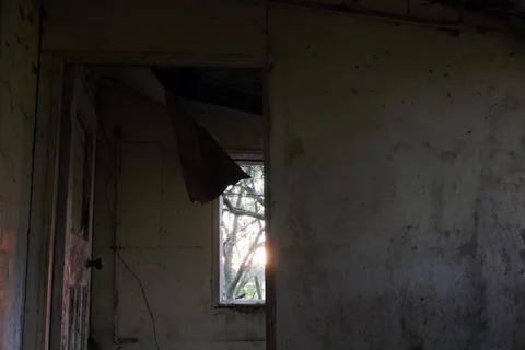 Looking out of a window at sunset in a spooky abandoned house. Stock Photos