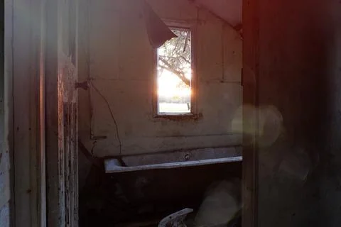 Looking out of a window at sunset in a spooky abandoned house. Stock Photos