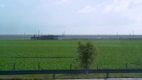 Looking outside a car window on a highway passing big agriculture field Video stock 273674212