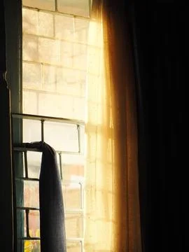 Looking outside through A window with a curtain drawn. Stock Photos