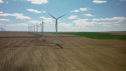 Looking over a dry, textured field of crops at windmill array. From a 库存影片 157257266