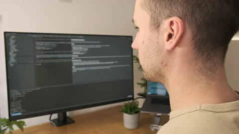Looking over the shoulder of a young professional programmer as he writes code Stock Footage 142611889