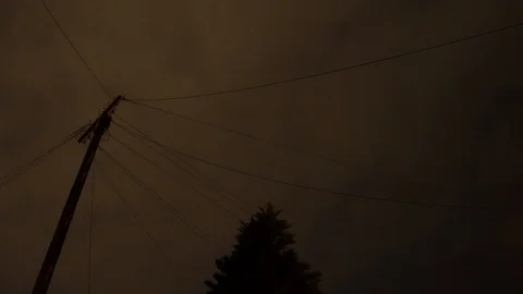 Looking up at power lines against a cloudy night sky Vídeo Stock 97856181