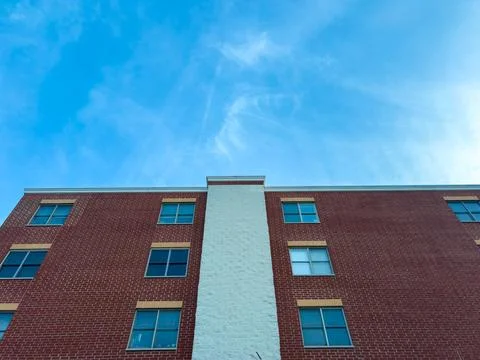 Looking up at a red brick building under a blue sky with a few clouds in th.. Stock Photos