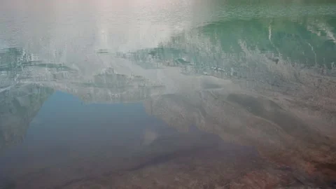 Looking at the reflection of a large mountain in the calm water of a remote lake Stock Footage 256592274