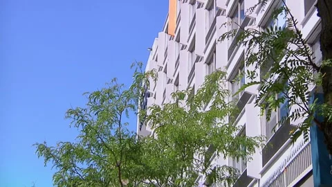 Looking up at residential skyscraper and bright blue sky 動画素材 323573585