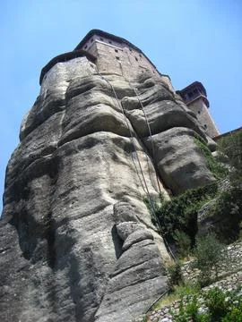 Looking up a rock formation with a Monastery at the top on a sunny day Stock Photos