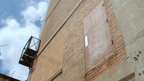 Looking up at a rusted door on a brick building wall. 4k60p Stock Footage 130144364