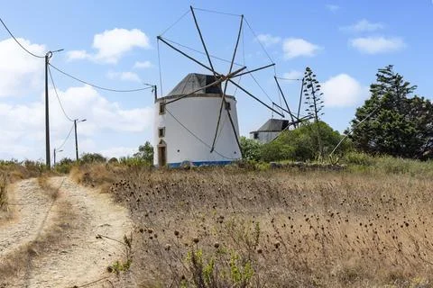 Looking up a rustic dirt path towards a classic Portuguese windmill in a fiel Stock Photos